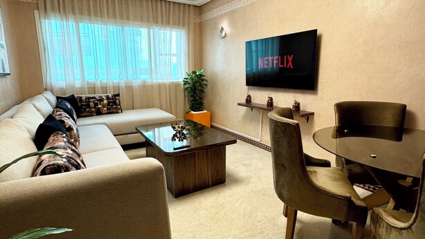 A living room with a sofa, coffee table, and a TV mounted on the wall.