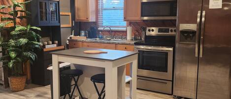 Una cocina moderna con paredes de madera, una isla central y electrodomésticos de acero inoxidable.