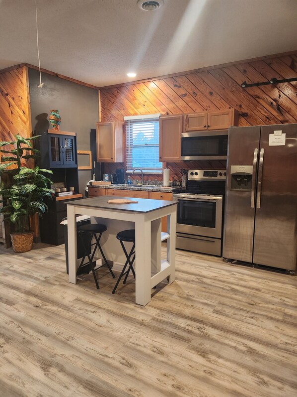 A modern kitchen with wooden walls, a central island, and stainless steel appliances.