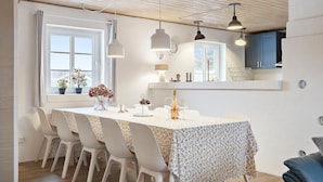 A dining area with a table set for four, white chairs, and pendant lighting. - Awesome home in Ringkøbing with sauna (Ringkøbing)