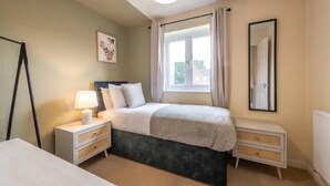 A bedroom with a bed, bedside tables, a window with curtains, a mirror, and a picture on the wall. - Charming Whitehurst Drive Nest in Manchester (Manchester)