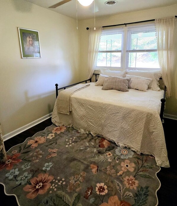 A bedroom with a bed, floral-patterned rug, and a picture on the wall. - Charming RiversideCottage- Firepit, Yard, pet friendly (Bridgewater)