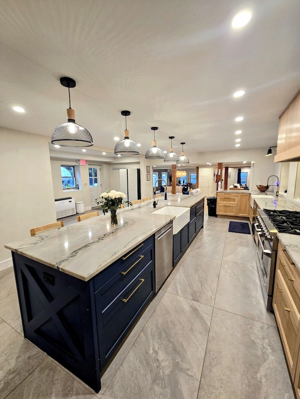 A modern kitchen with a large island, built-in appliances, and pendant lighting.