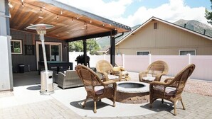 An outdoor patio with wicker furniture, a fire pit, and a covered area with string lights. - Delightful 3-bedroom house in Flagstaff (Flagstaff)