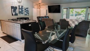 A modern kitchen with a central island, dining area with chairs, and a flat-screen TV mounted on the wall. - Delightful 3-bedroom house in Flagstaff (Flagstaff)