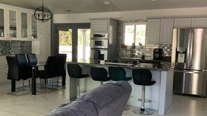 A modern kitchen with white cabinets, a central island, and stainless steel appliances. - Delightful 3-bedroom house in Flagstaff (Flagstaff)