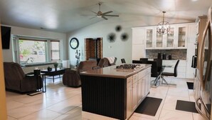 A modern kitchen with white cabinets, a central island, and a dining area with a sofa and chairs. - Delightful 3-bedroom house in Flagstaff (Flagstaff)