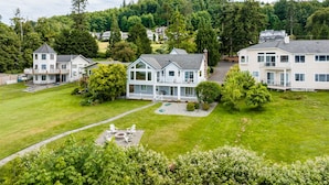 A residential area with multiple houses, a well-maintained lawn, and a fire pit area. - Waterfront Home with Game Room, Fireplaces, Kayaks, AC and Private Beach Access (Camano)