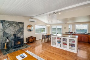 A spacious kitchen with a central island, a dining area with a round table, and a large window offering a view of the outdoors. - Waterfront Home with Game Room, Fireplaces, Kayaks, AC and Private Beach Access (Camano)