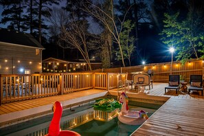 Ein Poolbereich im Garten mit Holzterrasse, Liegestühlen und einem Basketballkorb.