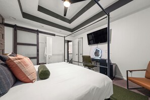 Ein Hotelzimmer mit einem Bett, einem Schreibtisch, einem Sessel, einem Fernseher und einer Schiebetür.