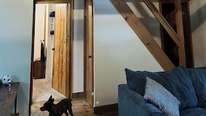 Ein Zimmer mit freiliegenden Holzbalken, einem blauen Sofa und einem Hund.