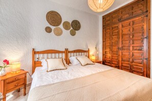 A bedroom with a wooden bed, bedside lamps, and a large wooden wardrobe.