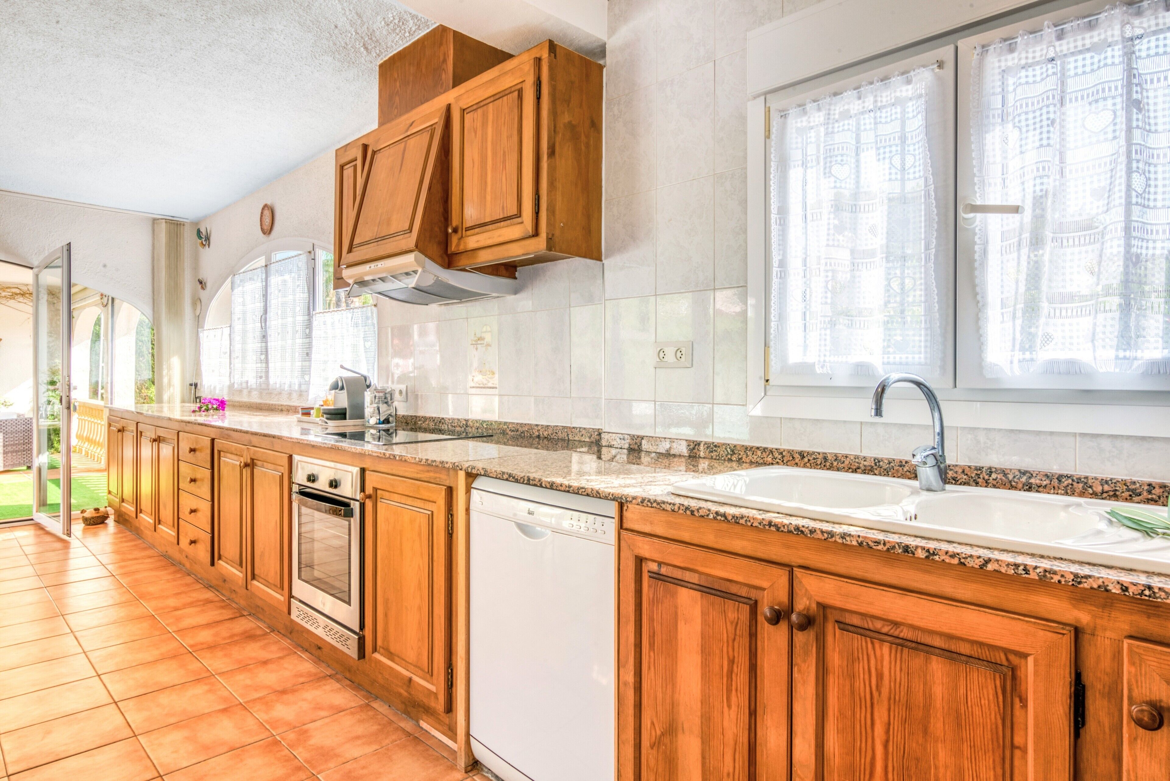 A kitchen with wooden cabinets, a dishwasher, and a double sink.