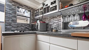 A modern kitchen with a microwave, stove, and a window above the sink. - Boat 'Port De Saint-Raphaël' with Sea View and Private Terrace (Saint-Raphaël)