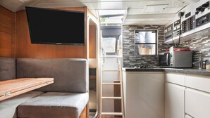 A compact RV kitchen with a built-in TV, a kitchenette, and a seating area with a foldable table. - Boat 'Port De Saint-Raphaël' with Sea View and Private Terrace (Saint-Raphaël)