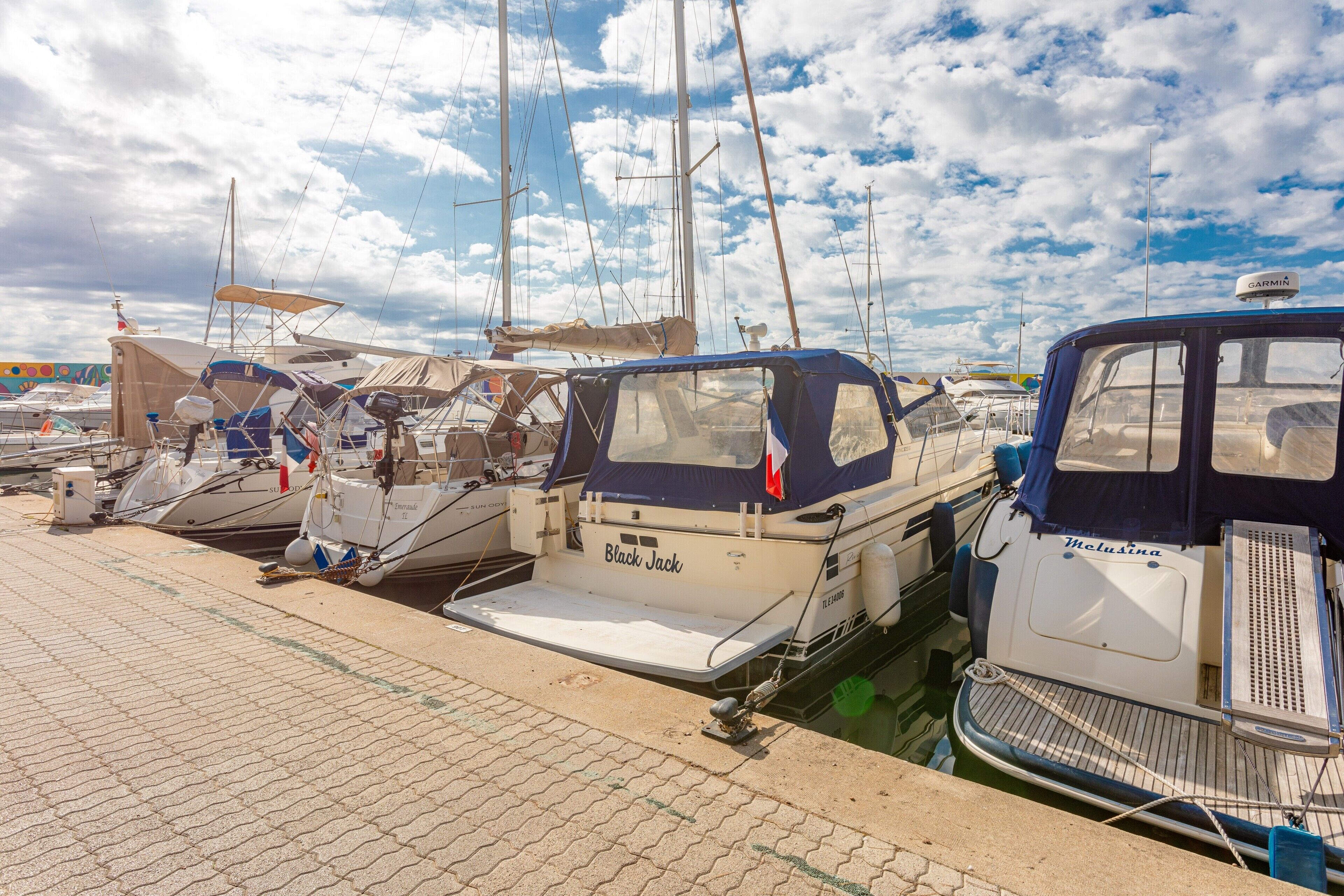 A marina with several boats docked, including a boat named 'Black Jack' and another named 'Helusina'.