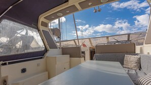A boat interior with a table, cushioned seating, and a view of the sky. - Boat 'Port De Saint-Raphaël' with Sea View and Private Terrace (Saint-Raphaël)