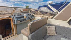 A boat's interior with a steering wheel, control panel, and seating area. - Boat 'Port De Saint-Raphaël' with Sea View and Private Terrace (Saint-Raphaël)