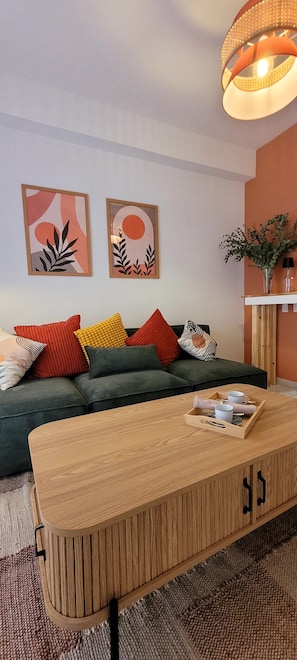Un soggiorno moderno con un divano, cuscini colorati, un tavolino in legno e due opere d'arte astratte appese alle pareti.