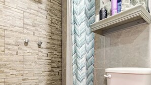 Ein Badezimmer mit Dusche, Toilette und Ablagen für Toilettenartikel.