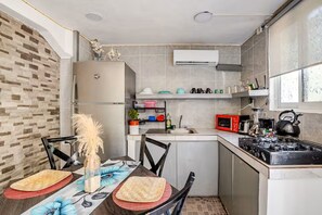 A compact kitchen with a refrigerator, microwave, stove, and a small dining area with a table and chairs.