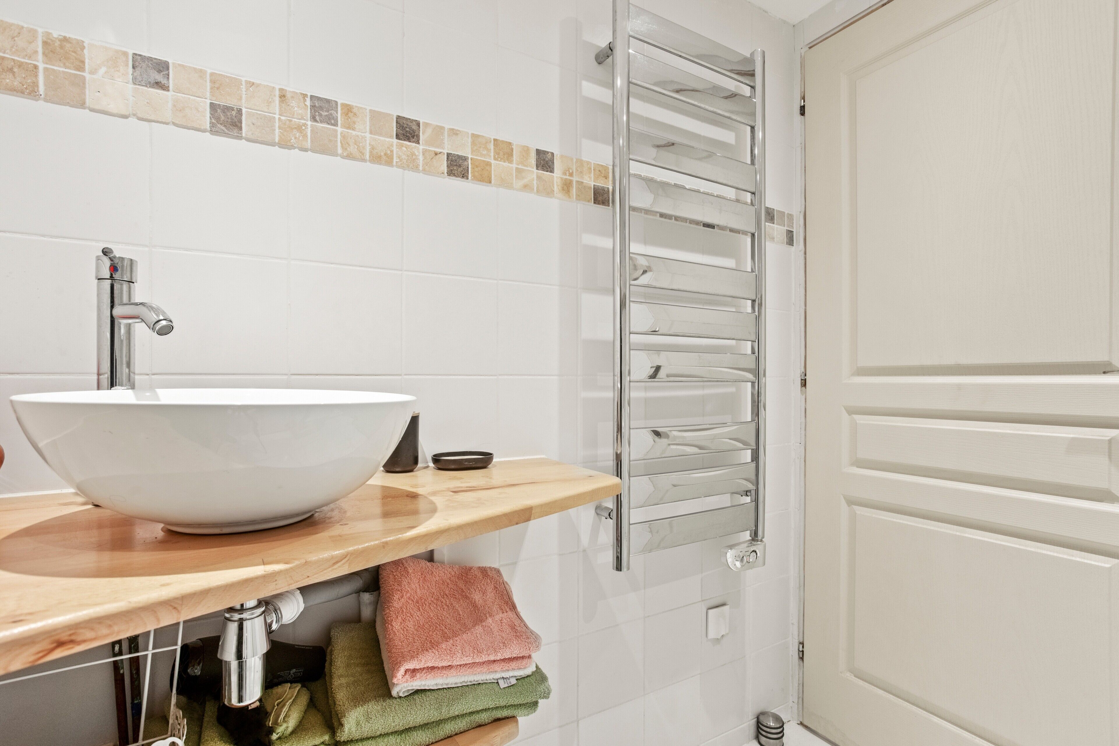 A bathroom with a white sink, a towel rack, and a door.
