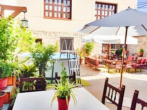 Eine Außenpatio mit Tischen, Stühlen und Blumentöpfen, sowie einem weißen Sonnenschirm.