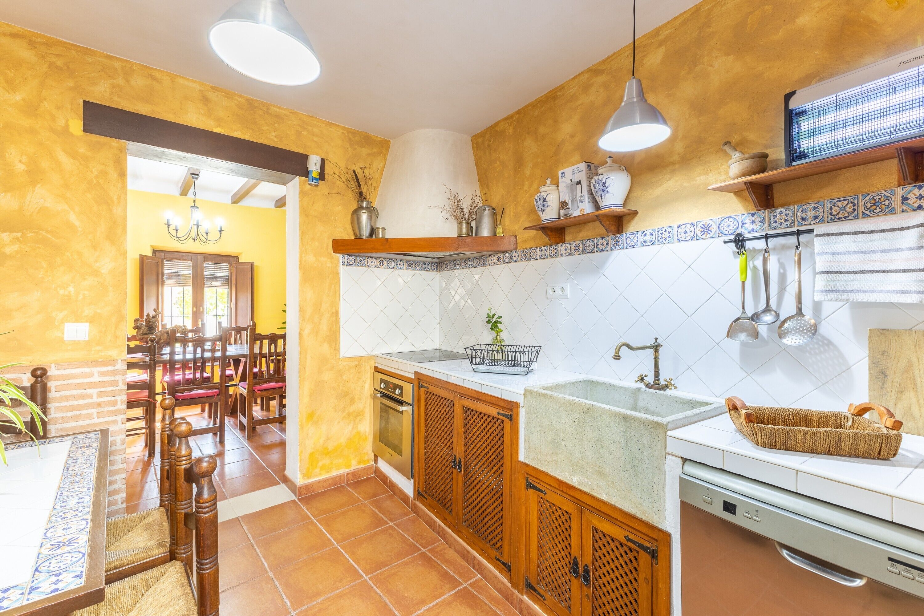 A kitchen with wooden cabinets, a sink, and a dining area with chairs and a table.