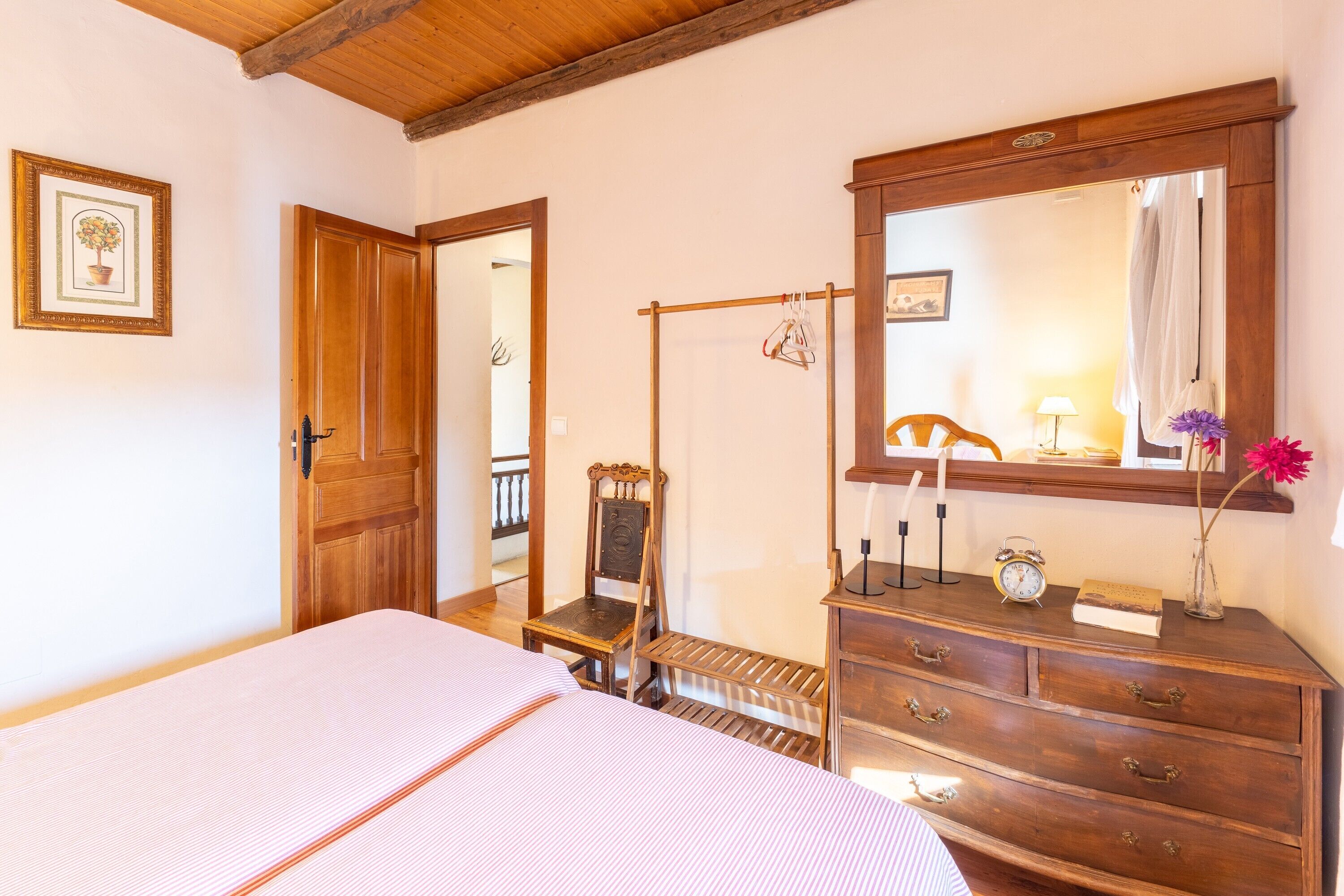 A room with a bed, a wooden dresser, a mirror, and a door.