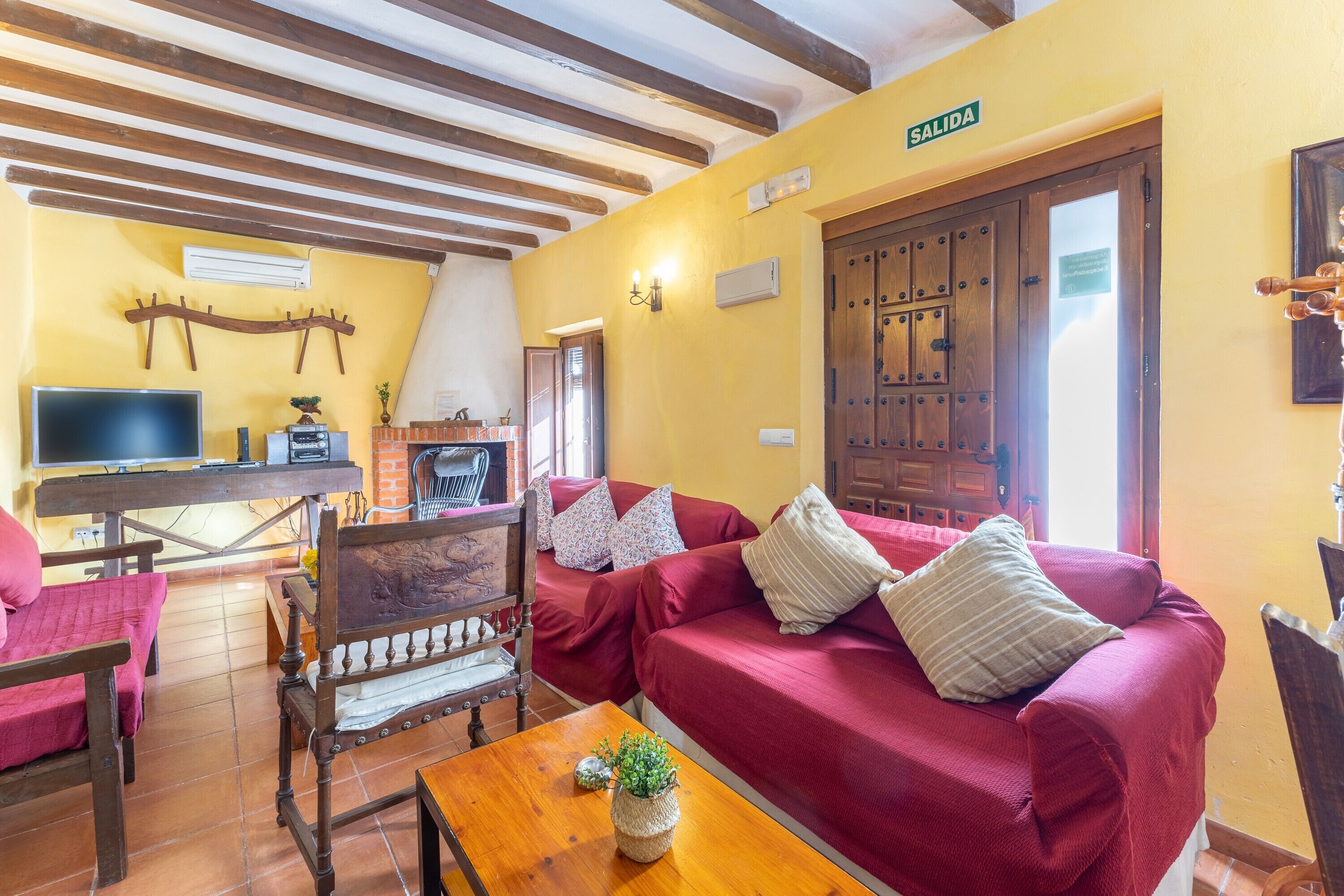 Un salón acogedor con techo de madera, televisor, sofá y mesa de madera.