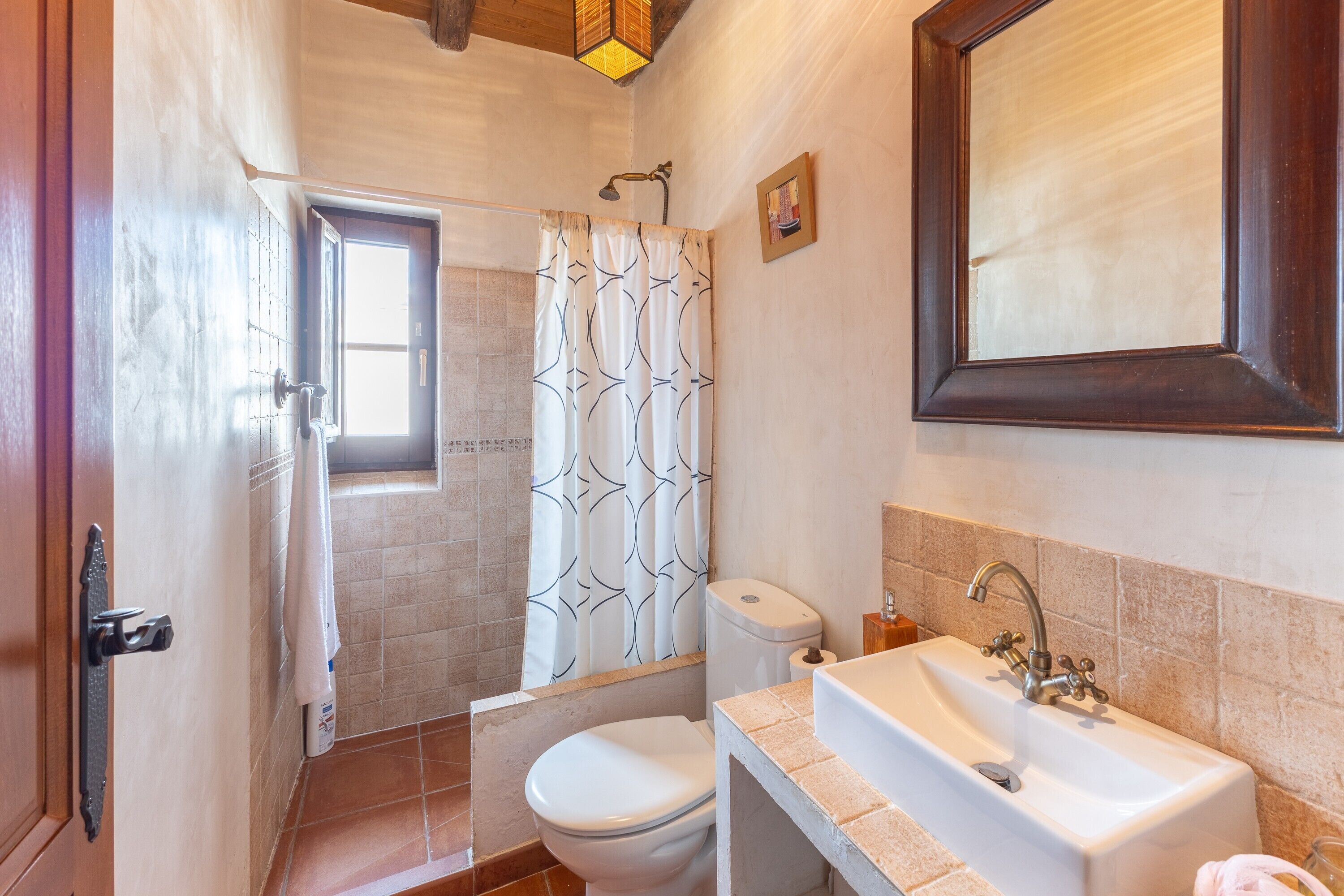 Un baño con ducha, inodoro, lavamanos y espejo.