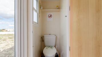 A small, compact bathroom with a toilet, a bidet, and a window.