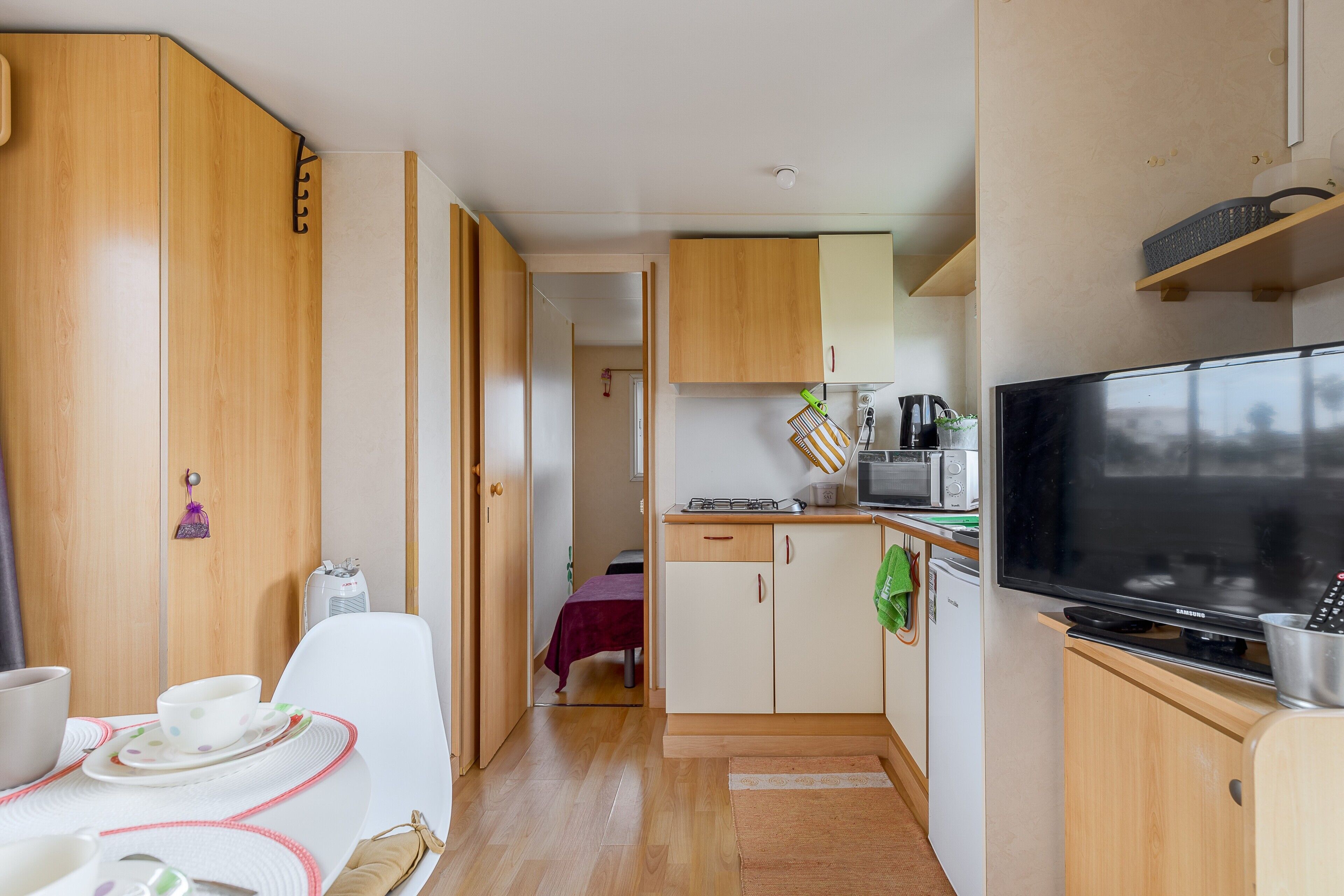 A compact kitchenette with a microwave, toaster, and a flat-screen TV.