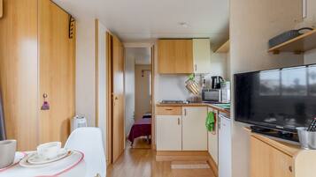 A compact kitchenette with a microwave, toaster, and a flat-screen TV.