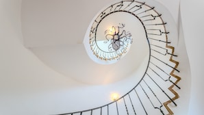 A spiral staircase with a decorative metal railing and a wall-mounted light fixture. - Holiday Home 'Villa La Veleta On Costa Brava' with Sea View, Private Pool and Wi-Fi (Begur)