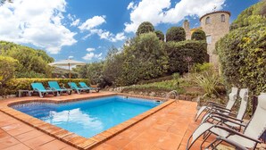A swimming pool with lounge chairs, a stone tower, and lush greenery. - Holiday Home 'Villa La Veleta On Costa Brava' with Sea View, Private Pool and Wi-Fi (Begur)