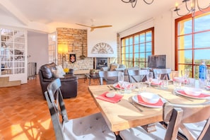 A dining area with a table set for four, a fireplace, and a stone wall.