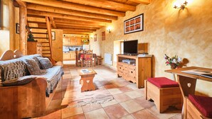A wooden interior with a sofa, a TV, and a dining area.