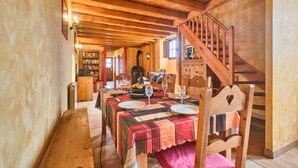 A wooden dining area with a table set for four, a wooden staircase, and a cozy interior.