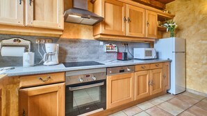 A kitchen with wooden cabinets, a built-in oven, a microwave, and a refrigerator.