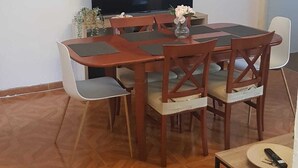 Een eethoek met een houten tafel en stoelen, een wandgemonteerde flatscreen-tv en een parketvloer met een patroon.
