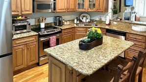 Una cocina con armarios de madera, encimera de granito, horno empotrado, microondas y un lavabo.