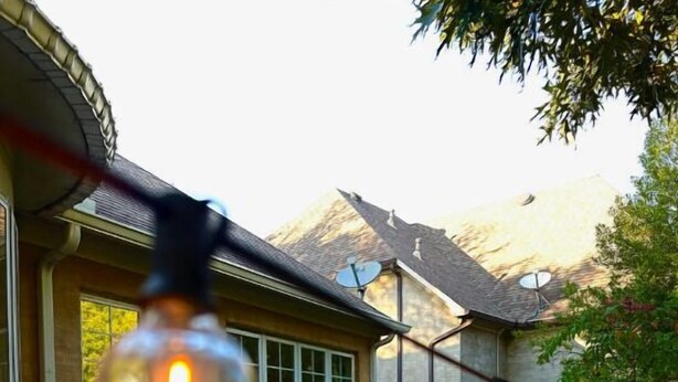 Un patio trasero con mobiliario exterior y luces colgantes.