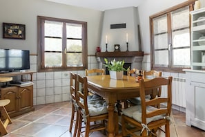 A dining area with a wooden table, chairs, a television, and a fireplace. - Country House 'Oiaraberri' with Private Garden and Wi-Fi (Erratzu)