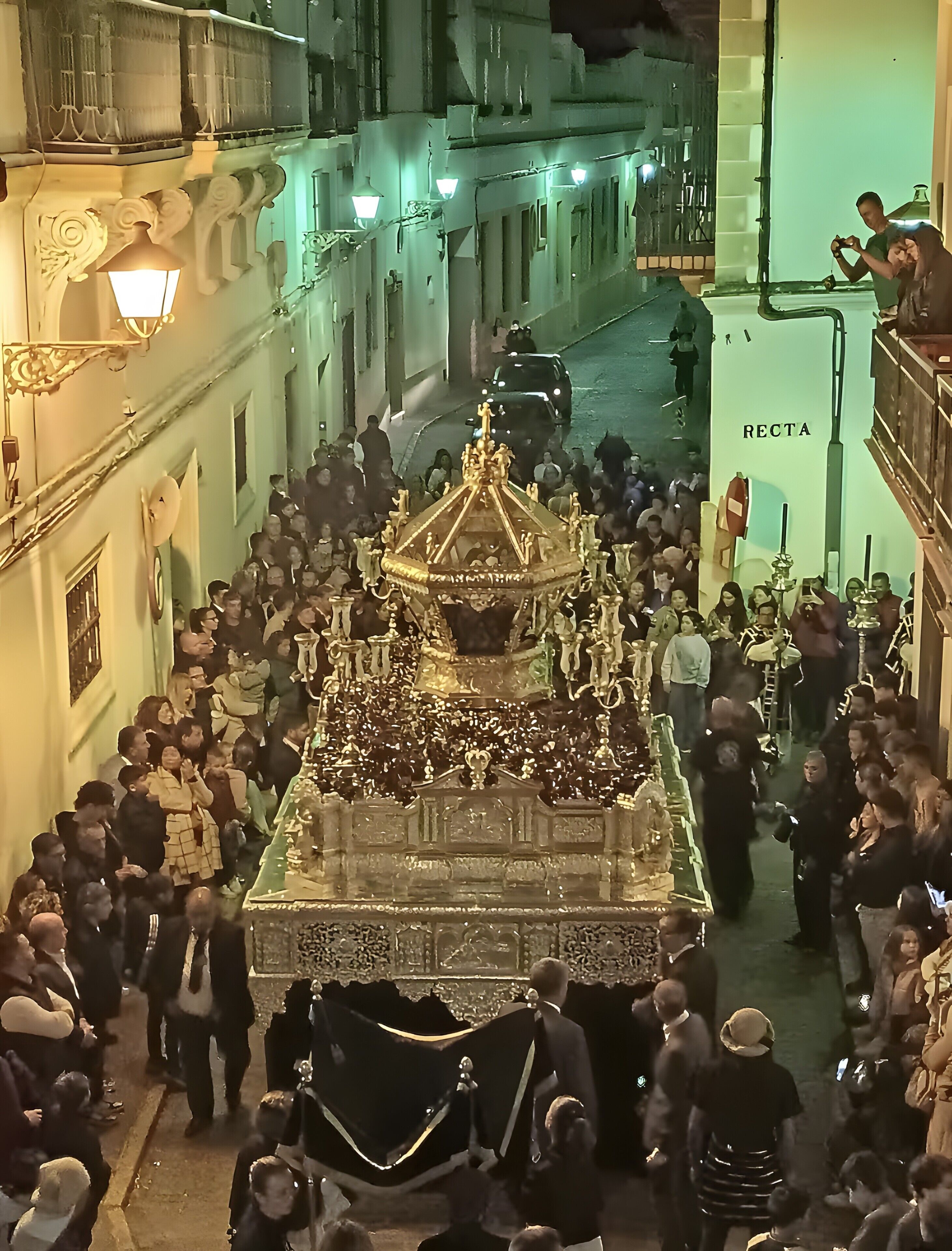 A crowd gathered around a large ornate structure, possibly a monument or statue, with a crowd of people and a vehicle in the background.