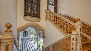 A grand staircase with marble steps and a checkered floor leading to an arched doorway.