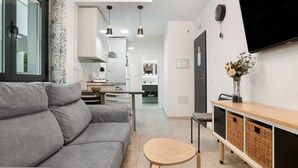 Una sala de estar moderna con un sofá gris, una mesita de madera y un televisor montado en la pared.