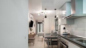 Una cocina moderna con comedor, electrodomésticos de acero inoxidable, iluminación colgante y vistas al salón.