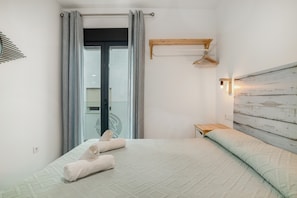 A bedroom with a bed, a hanging light, a wooden headboard, and a window with curtains.